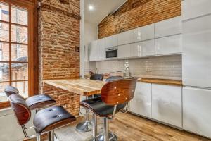 una cocina con una pared de ladrillo y una mesa y sillas de madera. en Charming and luxury flat in Toulouse - Welkeys en Toulouse