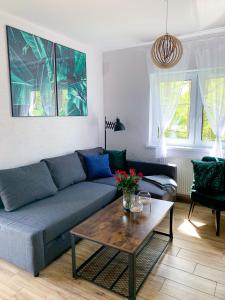 a living room with a blue couch and a coffee table at Apartamenty Szafirowa Mierzeja - 365PAM in Mielno