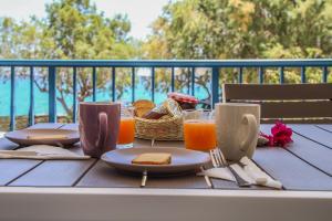 a table with a breakfast of toast and orange juice at MMM Apartment in Makry Gialos