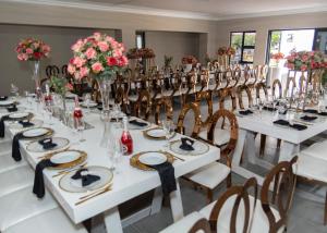 Cette grande chambre comprend des tables blanches, des chaises et des fleurs. dans l'établissement The Farm Boutique Guest House, à De Hoop 54 autres photos