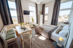 ein Schlafzimmer mit einem Bett und ein Wohnzimmer mit Fenstern in der Unterkunft Apartmenthaus Kaiser Friedrich in Potsdam