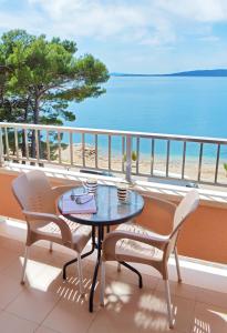 einen Tisch und Stühle auf einem Balkon mit Blick auf den Strand in der Unterkunft Villa Stina Drvenik in Drvenik