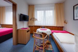 a room with two beds and a table and a tv at Hotel Horizont GmbH in Neubrandenburg