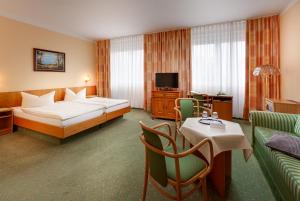 ノイブランデンブルクにあるHotel Horizont GmbHのベッド、テーブル、椅子が備わるホテルルームです。