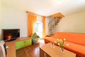 uma sala de estar com um sofá laranja e uma televisão em Villa Providenca em Kaštela