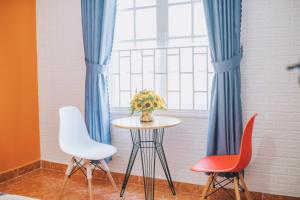 a table with two chairs and a window with blue curtains at Khải Hoàng 2 in Da Lat