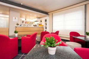un restaurante con mesas y sillas rojas y un bar en Best Western Hotel Residence Italia, en Quartu SantʼElena