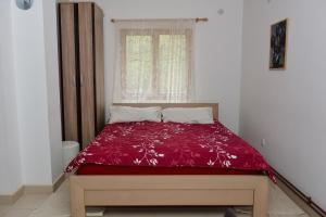 um quarto com uma cama com um edredão vermelho e uma janela em Bosa noga Rzav em Arilje