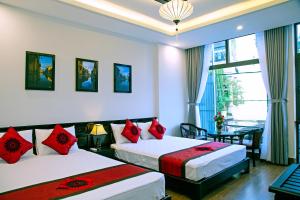 um quarto de hotel com duas camas com almofadas vermelhas em Green Sand Homestay em Hoi An