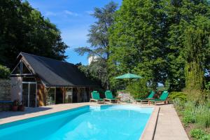 a swimming pool with green lounge chairs and an umbrella at Manoir de Beauregard - Cunault in Trèves-Cunault