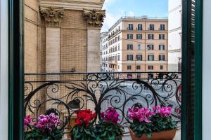 einen Balkon mit Blumen in Töpfen auf einem Zaun in der Unterkunft Hotel Tritone in Rom