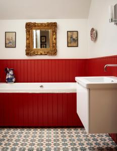 een rode badkamer met een bad en een spiegel bij Newhall Mains in Resolis