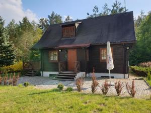 una piccola casa in legno con un ombrello di fronte di Plaża Resort a Bogaczewo