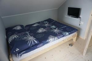 a small bed with blue and white blankets and a tv at OSADA CZTERY PORY ROKU - DOM ZIMA in Kopalino