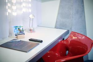 a desk with a laptop and a red chair at CIP Hôtel in Tramelan