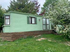 a green tiny house on top of a yard at Private Countryside Holiday Cabin 10 mins from Brighton in Brighton & Hove