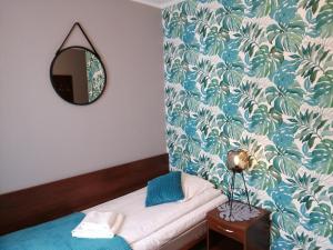 um quarto com uma cama com um espelho e um papel de parede azul e branco em Platinum em Budzyń