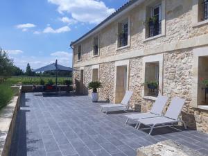 eine Terrasse mit 2 Stühlen und ein Gebäude in der Unterkunft DOMAINE DE GUILLEMIN in Saint-Louis-de-Montferrand