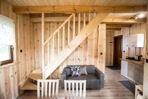 a room with a wooden wall with a couch and stairs at Domki PAGAJ in Zwierzyniec