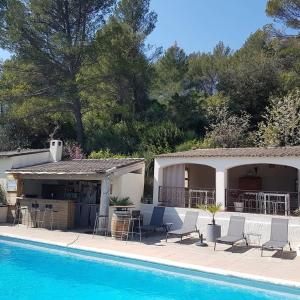 una piscina con sillas, una mesa y una casa en Villa Manoe, en Draguignan