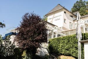 a white building with a tree in front of it at Hennedamm Hotel in Meschede