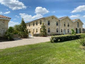 Saint-Louis-de-Montferrand的住宿－DOMAINE DE GUILLEMIN，一座带草地庭院的大型石头建筑