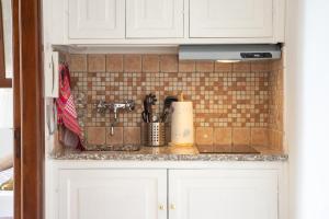 a kitchen with white cabinets and a tile wall at Scalinatella in Positano