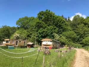 a group of huts in a field next to a dirt road at Shepherds Huts Ham Hill, 2 double beds, Bathroom, Lounge, Diner, Kitchen, LOVE dogs & Cats Looking out to lake and by Ham Hill Country Park plus parking for large vehicles available also great deals on workers long term This is the place to relax and BBQ in Yeovil