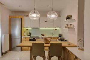 a kitchen with a wooden table with chairs and two lights at NOURI APARTMENT in Corfu