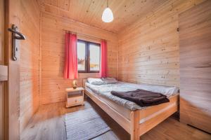 ein Schlafzimmer mit einem Bett in einer Holzhütte in der Unterkunft Morska Bryza in Sarbinowo