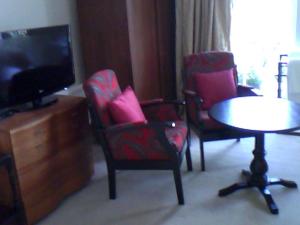 多佛的住宿－7號修道院旅館，客厅配有两把椅子、一张桌子和一台电视