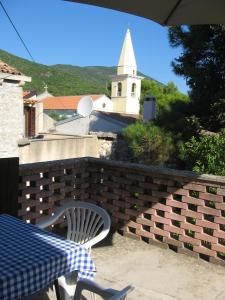 a table and chair on a brick wall with a church at 3 bedrooms house at Sveti Jakov 400 m away from the beach with enclosed garden and wifi in Sveti Jakov