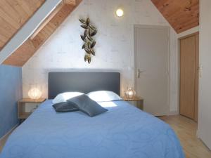 1 dormitorio con 1 cama azul y 2 almohadas en La Fermette du Rohiou, en Le Faouët