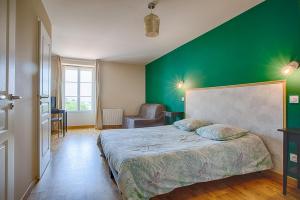 a bedroom with a green wall and a bed at La maison d'Hana in Saint-Bonnet-de-Valclérieux