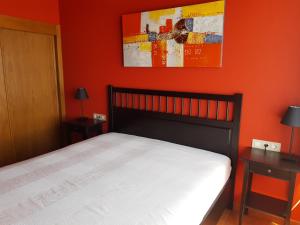 um quarto com uma cama com uma parede laranja em Vistas al Sueve em Colunga