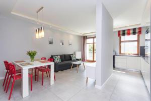 eine Küche und ein Wohnzimmer mit einem Tisch und roten Stühlen in der Unterkunft Apartament Sopocka Przystań in Sopot