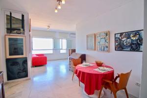 sala de estar con mesa roja y sillas en Apartamento VENTANAL AL MAR (Free Parking), en Cádiz