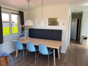 a dining room with a wooden table and blue chairs at Olmenduin | Chalet 26 | Zeeland in Serooskerke
