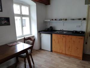 eine Küche mit einem Waschbecken, einem Tisch und einem Fenster in der Unterkunft Dům u řeky in Vyšší Brod