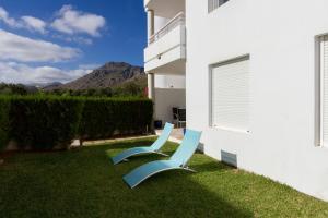 twee blauwe stoelen op het gras naast een gebouw bij Ground Floor with private garden Bellresguard in Port de Pollença