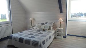 ein Schlafzimmer mit einem Bett mit zwei Nachttischen und zwei Fenstern in der Unterkunft Les Chambres des Badious in Plerguer