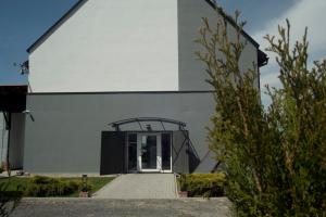 a large white building with a glass door at Apartamenty Folwark Boguszyn in Kłodzko