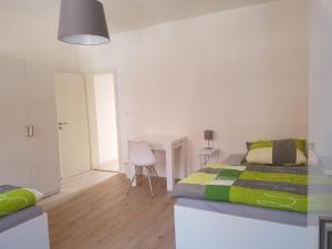 a white bedroom with a bed and a desk at Ferienwohnung in Brackenheim +3 photos
