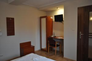 a bedroom with a bed and a desk with a television at Boho Hotel i Restauracja in Ostrów Wielkopolski