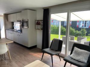 a kitchen with white cabinets and chairs and a window at olmenduin 33 in Serooskerke