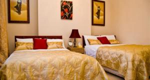 1 dormitorio con 2 camas con almohadas doradas y rojas en No 7 Priory Guest House, en Dover