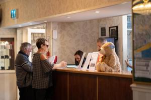 un grupo de personas de pie en un mostrador con un oso de peluche en Bournemouth Sands Hotel, en Bournemouth