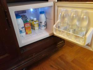 an open refrigerator filled with bottles of water and milk at Petit Chateau in Montecatini Terme