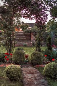 a garden with bushes and red flowers and a fence at Natura Airport Apartment in Belgrade