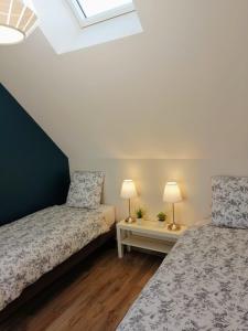a bedroom with two beds and two lamps on tables at Le petit Mérinos - Rambouillet - in Rambouillet